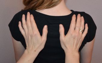 Auf dem Foto sieht man den Rücken einer Frau, auf dem zwei Hände liegen.