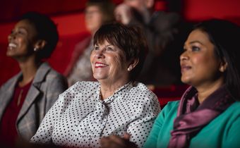 Auf dem Bild sieht man drei Frauen, die im Kino sitzen und sich einen Film anschauen.