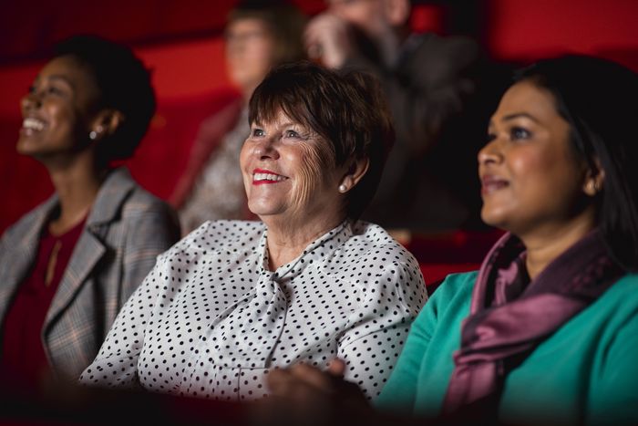 Auf dem Bild sieht man drei Frauen, die im Kino sitzen und sich einen Film anschauen.