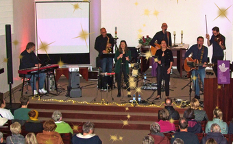 Acht Musikerinnen und Musiker stehen auf der Bühne und spielen vor einem Publikum in Dülmen.