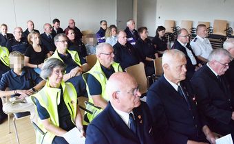 Auf dem Foto sieht man Menschen auf Stühlen in einem Raum sitzen. Sie feiern einen Gottesdienst