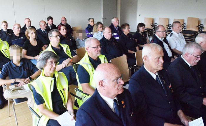 Auf dem Foto sieht man Menschen auf Stühlen in einem Raum sitzen. Sie feiern einen Gottesdienst
